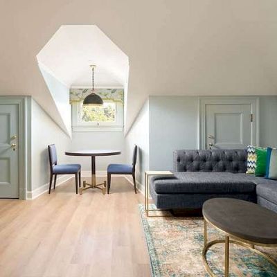 A modern living room with gray sofas, colorful pillows, framed wall art, a TV cabinet, and a skylight ceiling.