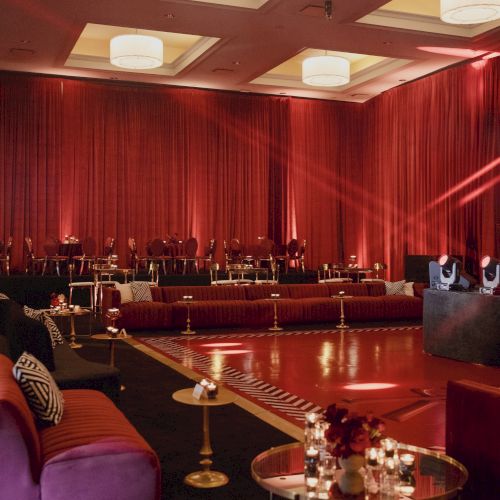 A chic hotel lounge or club with red drapes, warm lighting, plush seating, candles, and a stylish bar area in a glossy, elegant setting.